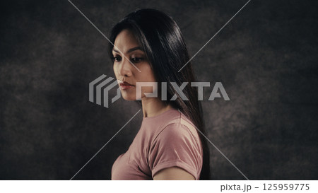 Young Asian Woman with Long Black Hair Posing in Studio with Dark Background Young Asian Woman with Long Black Hair Posing in Studio with Dark Background 125959775