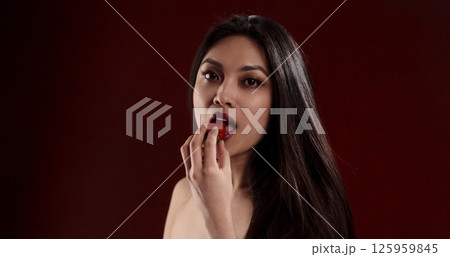 Beautiful Asian Woman Eating Strawberry in Studio with Red Background 125959845