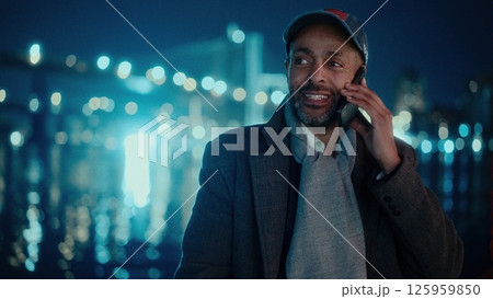 Businessman smiling while talking on phone in Manhattan at night 125959850