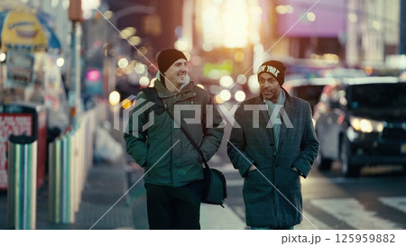 Two men walking and talking on a Manhattan street at sunset Two men walking and talking on a Manhattan street at sunset 125959882