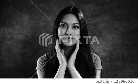 Young woman holding her face with hands, black and white portrait 125960010
