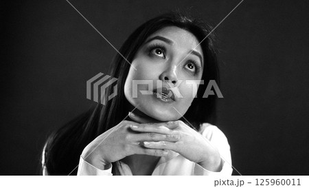 Young Asian Woman Looking Up with Hope and Wonder in Studio Portrait 125960011