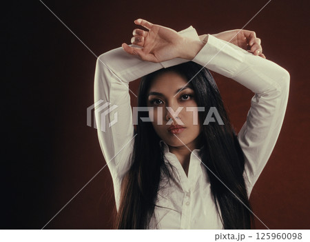 Confident Asian businesswoman posing with arms raised in studio setting 125960098