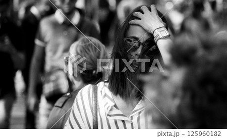 Young woman adjusting hair while standing in a crowd in Paris Young woman adjusting hair while standing in a crowd in Paris 125960182