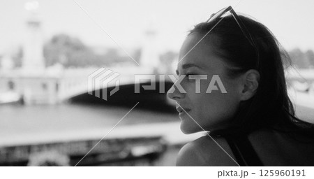 Woman enjoying Paris from Seine river contemplating bridge in black and white 125960191