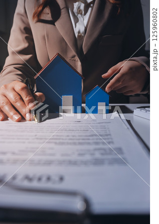 Female Real Estate Broker presenting and advised to model home and building project detail in the office, sign purchase sales contract, agreements concerned mortgage loan offer and insurance. Female Real Estate Broker presenting and advised to model home and building project detail in the office, sign purchase sales contract, agreements concerned mortgage loan offer and insurance. 125960802