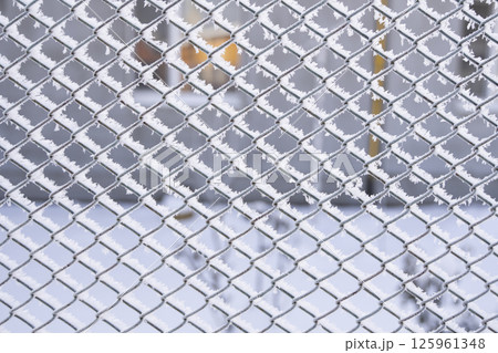 Frost-covered steel fence pattern with hoarfrost in cold winter morning light Frost-covered steel fence pattern with hoarfrost in cold winter morning light 125961348