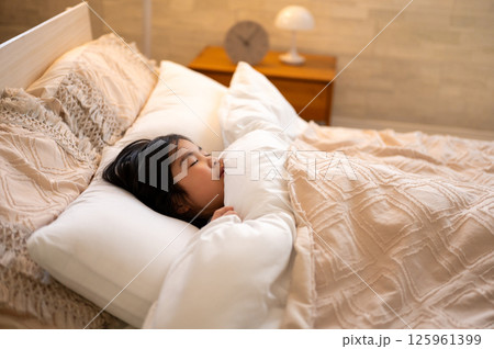 広いベッドで目を閉じて気持ちよさそうに眠る女の子のナチュラルな姿 125961399