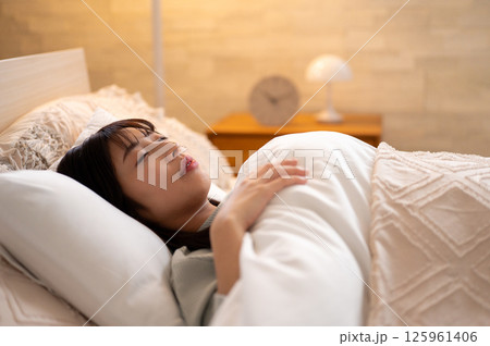 朝の光を浴びながらベッドに横たわる女性の静かな目覚めのひととき 125961406