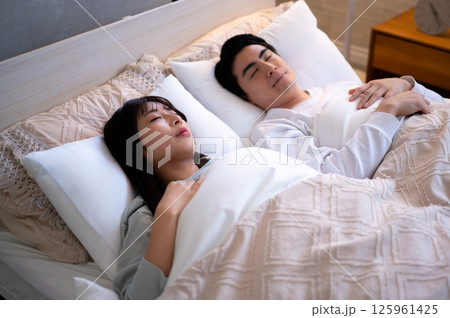 並んで布団に入り穏やかに眠るカップルの静かな寝室のひととき 125961425