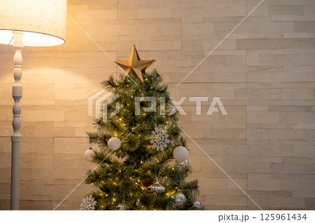 壁際に設置されたライトとクリスマスツリーが暖かく空間を彩る室内装飾 壁際に設置されたライトとクリスマスツリーが暖かく空間を彩る室内装飾 125961434
