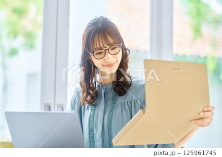 パソコンを見ながら荷物の確認をする若い女性 125961745