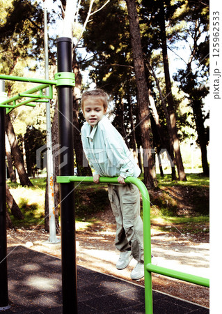 little cute girl having fun on training playground outside little cute girl having fun on training playground outside 125962533