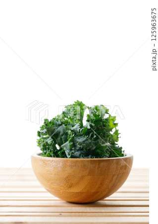 Fresh green Kale leaf salad vegetable in wooden bowl on white background. 125963675