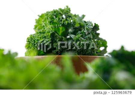 Fresh green Kale leaf salad vegetable in wooden bowl on white background. Fresh green Kale leaf salad vegetable in wooden bowl on white background. 125963679