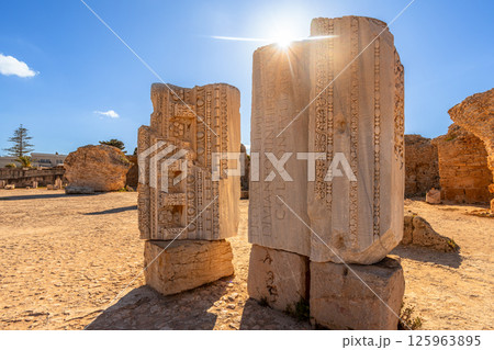 Sunlit ruins and stones with Roman inscriptions throwing shadows, Baths of Antoninus, ancient Carthage, Tunis, Tunisia Sunlit ruins and stones with Roman inscriptions throwing shadows, Baths of Antoninus, ancient Carthage, Tunis, Tunisia 125963895