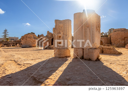 Sunlit ruins and stones with Roman inscriptions throwing shadows, Baths of Antoninus, ancient Carthage, Tunis, Tunisia 125963897