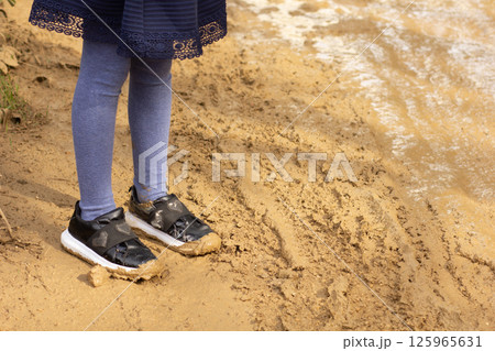 Child legs with shoes in mud outside 125965631