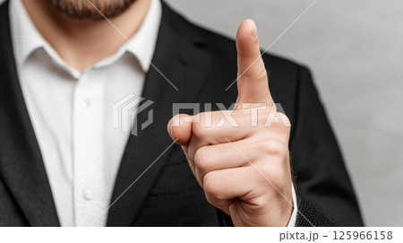 A businessman in a suit touching a finger on a virtual screen, isolated over a light gray background.  125966158