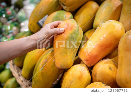 Tourist hand checking ripe soft papaya selecting best piece at market fruit counter, food shopping 125967751