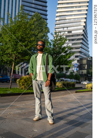 Serious african man strolling on sidewalk, walking to college, heading home after university classes 125967878