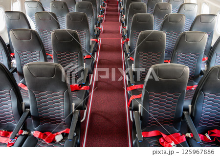 Empty interior of cabin of airplane with rows of black and red seats, high angle view 125967886