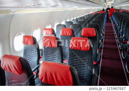 Empty interior of cabin of airplane with rows of black and red seats in daytime before the flight Empty interior of cabin of airplane with rows of black and red seats in daytime before the flight 125967887