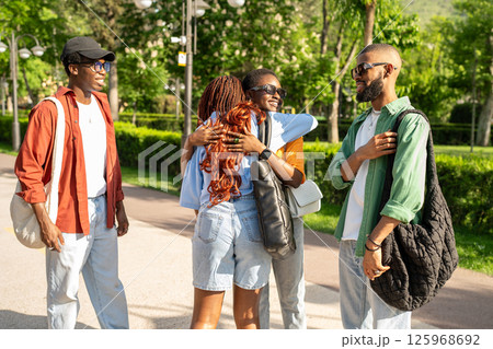 Close African student friends reunite outside, hugging embracing with laughter and joy, end of exams 125968692