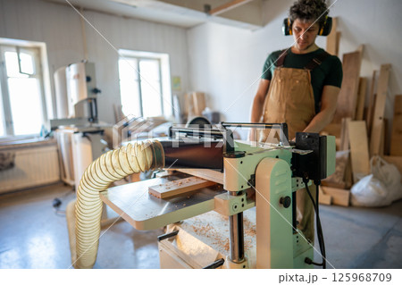 Band saw machine operating. Concentrated craftsman woodworking in studio, finalizing project 125968709