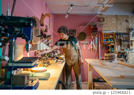 Attentive workshop owner carpenter organizing tools and cleans work area before starting daily tasks 125968821
