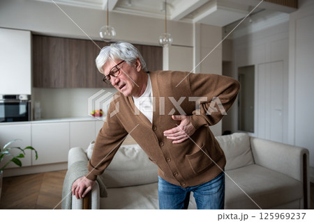 Sudden chest discomfort. Elderly man clutches chest in agony struggling to breathe in heart attack 125969237