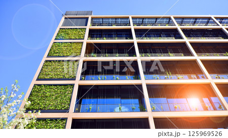 Green office building with plants on the facade. Ecology and green living in city, urban environment concept. Eco architecture. Green office building with plants on the facade. Ecology and green living in city, urban environment concept. Eco architecture. 125969526