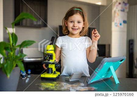 Little girl examining onion skin under a microscope. Concept of early science education and cell structure exploration Little girl examining onion skin under a microscope. Concept of early science education and cell structure exploration 125970160