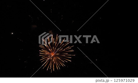 Fireworks magic creates shimmering trace ornaments in black night sky. Spellful firework explosions on display color dark sky. Firework show with glowing patterns in evening sky at holiday party Fireworks magic creates shimmering trace ornaments in black night sky. Spellful firework explosions on display color dark sky. Firework show with glowing patterns in evening sky at holiday party 125971029