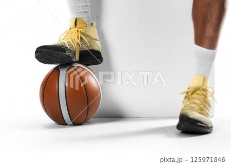 Basketball. Focus on the ball. Close-up. Basketball player's foot on the ball. Professional basketball on a white background 125971846