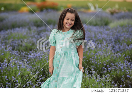 Happy girl twists her dress in a lavender field. 125971887