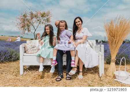 Children with their parents are resting on a lavender field. 125971903