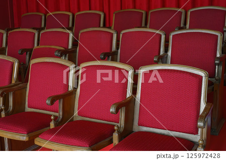 EnEmpty rows of retro red theater or cinema seats with red upholstery EnEmpty rows of retro red theater or cinema seats with red upholstery 125972428