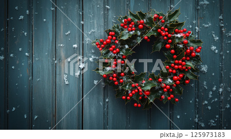 Holly wreath with red berries hanging on snowy wooden wall Holly wreath with red berries hanging on snowy wooden wall 125973183