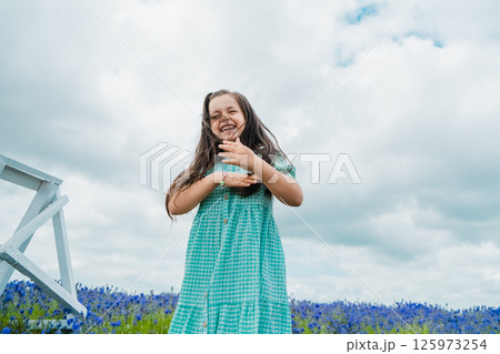 A cheerful girl of European appearance is jumping merrily in a beautiful field. 125973254