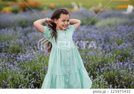 A little girl fixes her hair on a lavender field. A little girl fixes her hair on a lavender field. 125973435