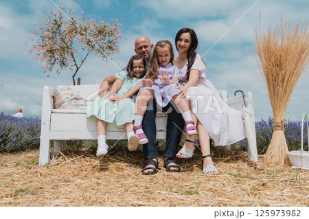 A family resting on a beautiful white bench. A family resting on a beautiful white bench. 125973982