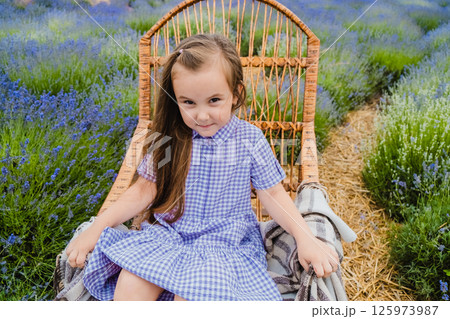 The girl in the lavender field is sitting in a rocking chair covered with a thin blanket. The girl in the lavender field is sitting in a rocking chair covered with a thin blanket. 125973987