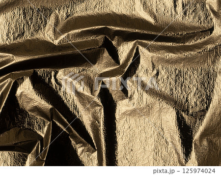 Golden foil with a shiny, polished sheen. Elegant, reflective fabric with a crumpled texture and Golden foil with a shiny, polished sheen. Elegant, reflective fabric with a crumpled texture and 125974024