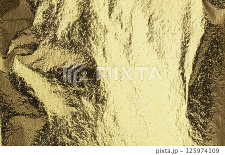 gold foil surface with striking creases and reflective shine. The texture has a soft, draped gold foil surface with striking creases and reflective shine. The texture has a soft, draped 125974109