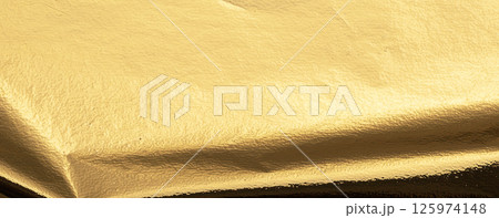 Gold metallic foil texture with a folded, smooth surface. Shiny, reflective material in warm yellow 125974148