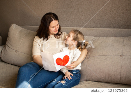 Mom and daughter celebrating 8 march, birthday, mothers day. Little preschool daughter surprising mom with handmade greeting card with painting. 125975865