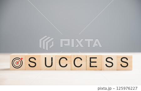 Wooden cube placed over the word success on a wood table, highlighting the target success concept. Captured on a grey background with ample copy space. Wooden cube placed over the word success on a wood table, highlighting the target success concept. Captured on a grey background with ample copy space. 125976227