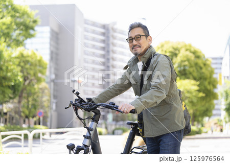 自転車をおして歩く50代後半の男性 自転車をおして歩く50代後半の男性 125976564