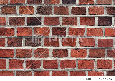 Brick wall with varied color tones, showcasing a rustic and textured appearance from a close perspective. 125976973